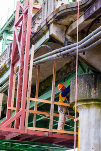 Workman inspecting underneath bridge