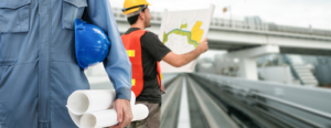 Workmen in safety gear while standing on bridge and reading bridge plans