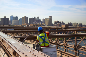 bridge repair specialist lifted in bucket while making repairs to bridge