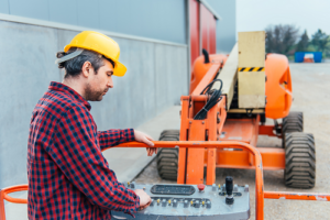 worker wearing yellow helmet standing inside boom lift