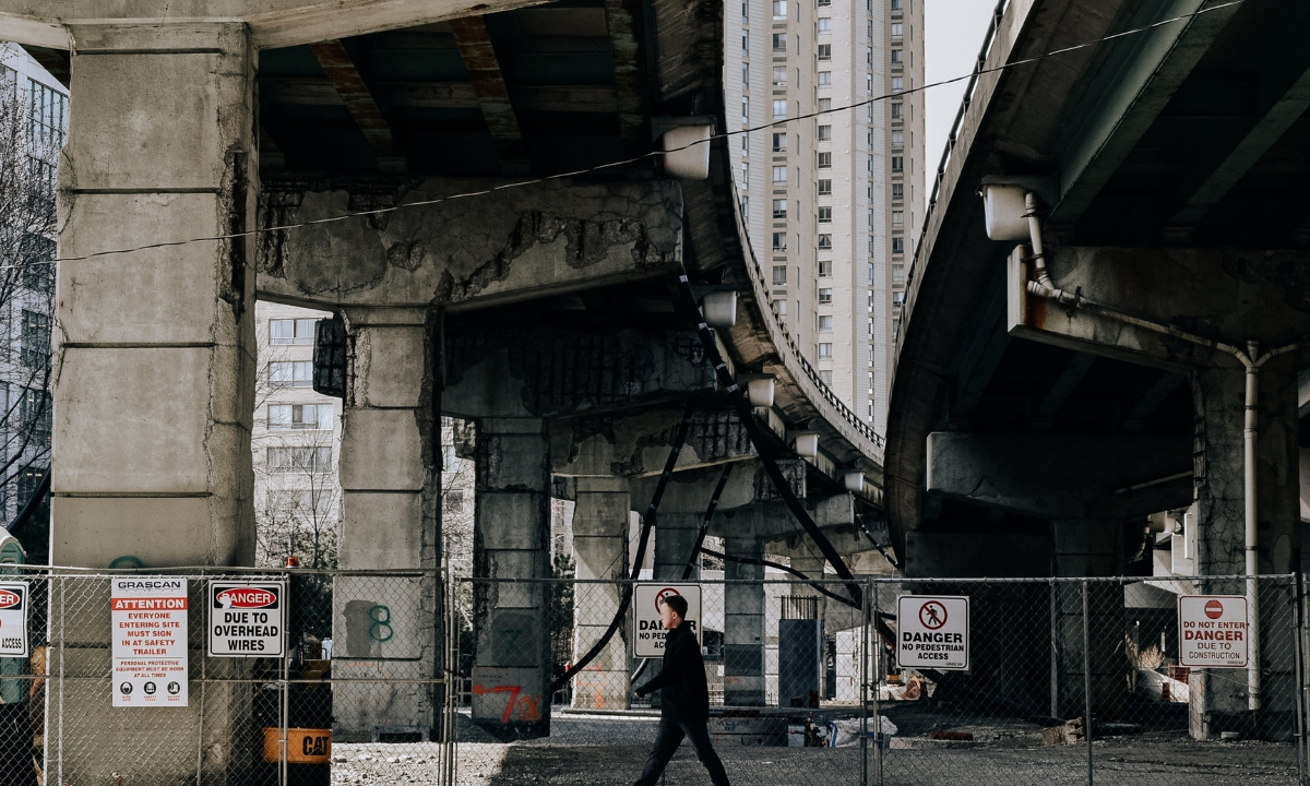 a person walking beneath and past an old-looking bridge