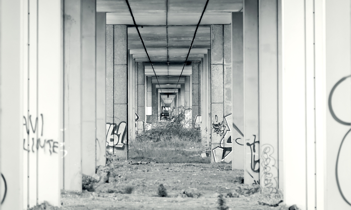 a black and white image of underneath an old bridge with graffiti on it