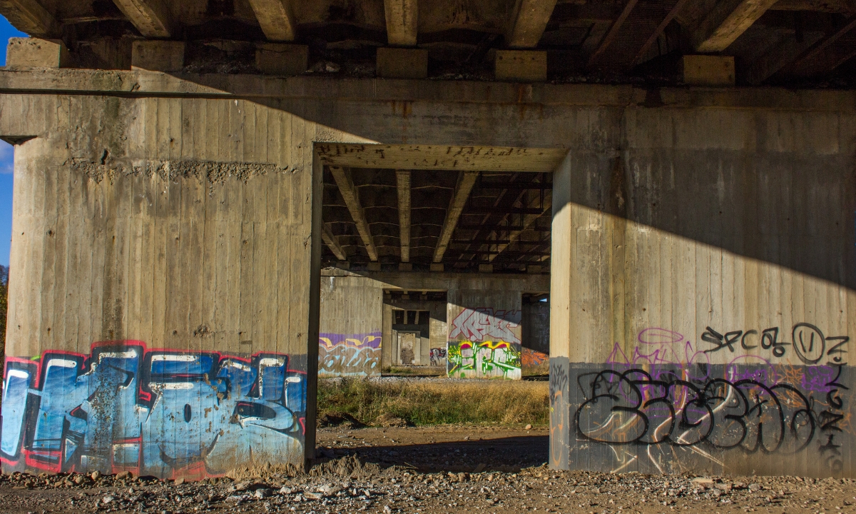 the supports and underside of a bridge, the supports are graffitied 