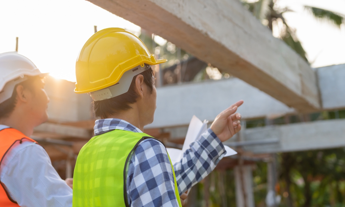 two people looking at a bridge being built, one is pointing at it and seems to be about to say something